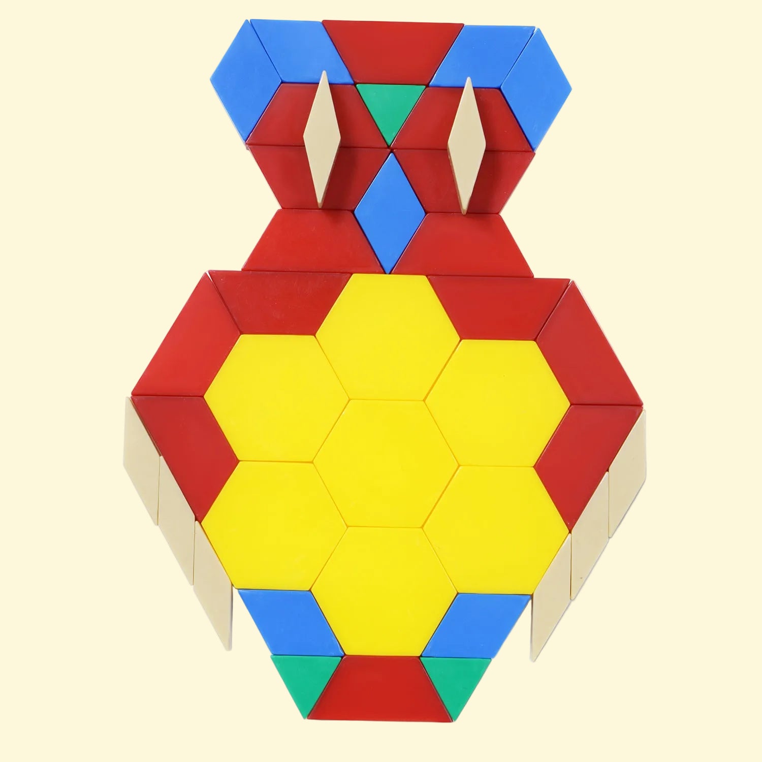 A colorful geometric block puzzle or toy structure assembled into a symmetrical vase-like shape, featuring a large yellow central hexagon area surrounded by red, blue, green, and beige pieces, photographed on a butter background.