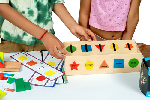 Children playing with a wooden shape sorting toy and pattern cards on a table.