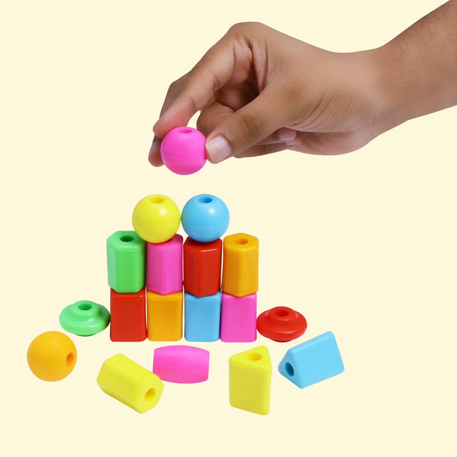 Child's hand stacking a pink Bead Wizard bead on a colourful pyramid